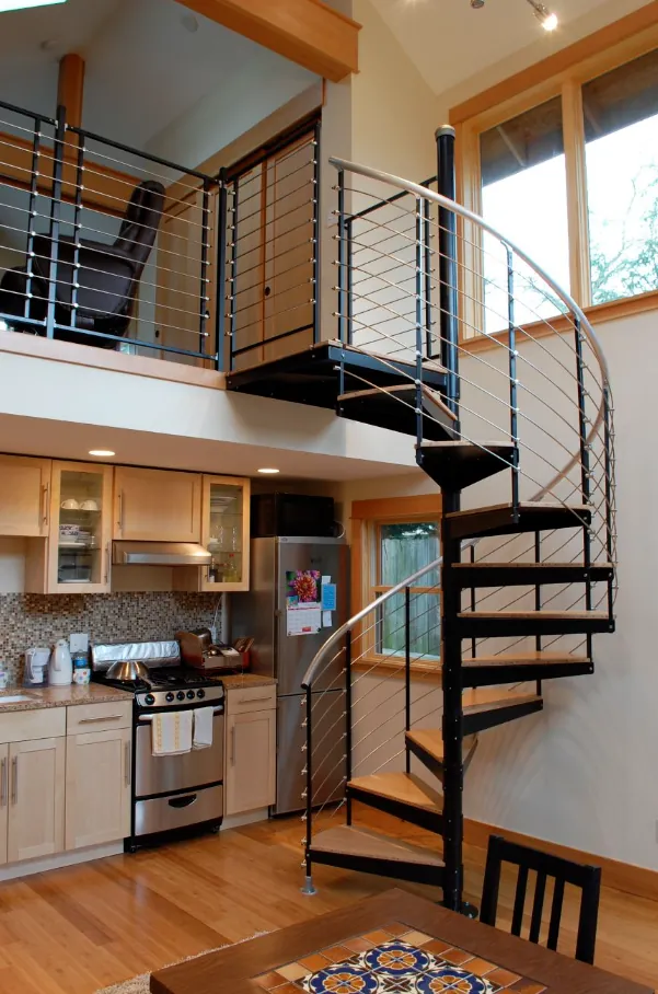 ADU interior with a black spiral staircase up to a loft over the kitchen