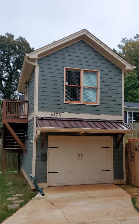 Two-storey garage suite with a carriage-style garage door and an outside stair to the suite above